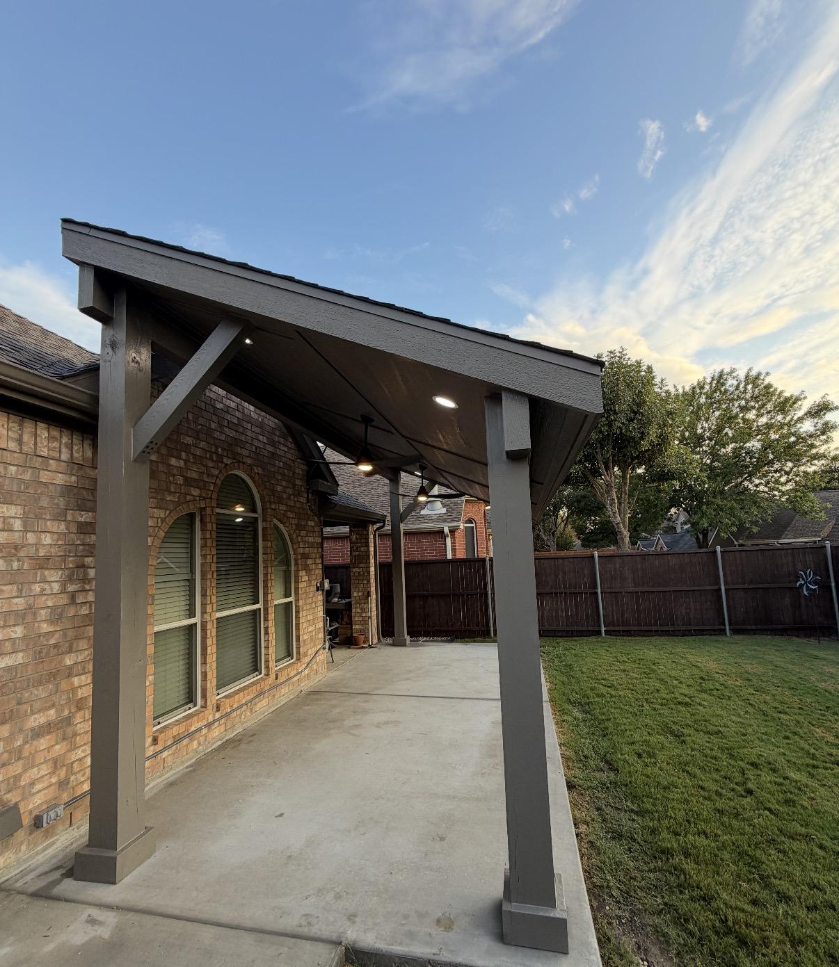 Free-standing charcoal patio cover with recessed lighting over a new concrete patio and lawn in Dallas-Fort Worth