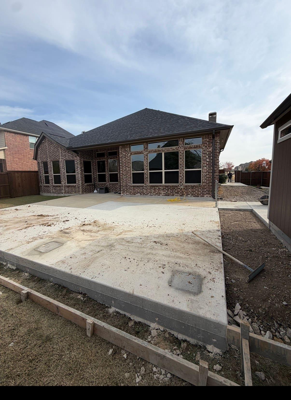 Freshly poured and finished concrete patio slab behind a brick home in Dallas-Fort Worth
