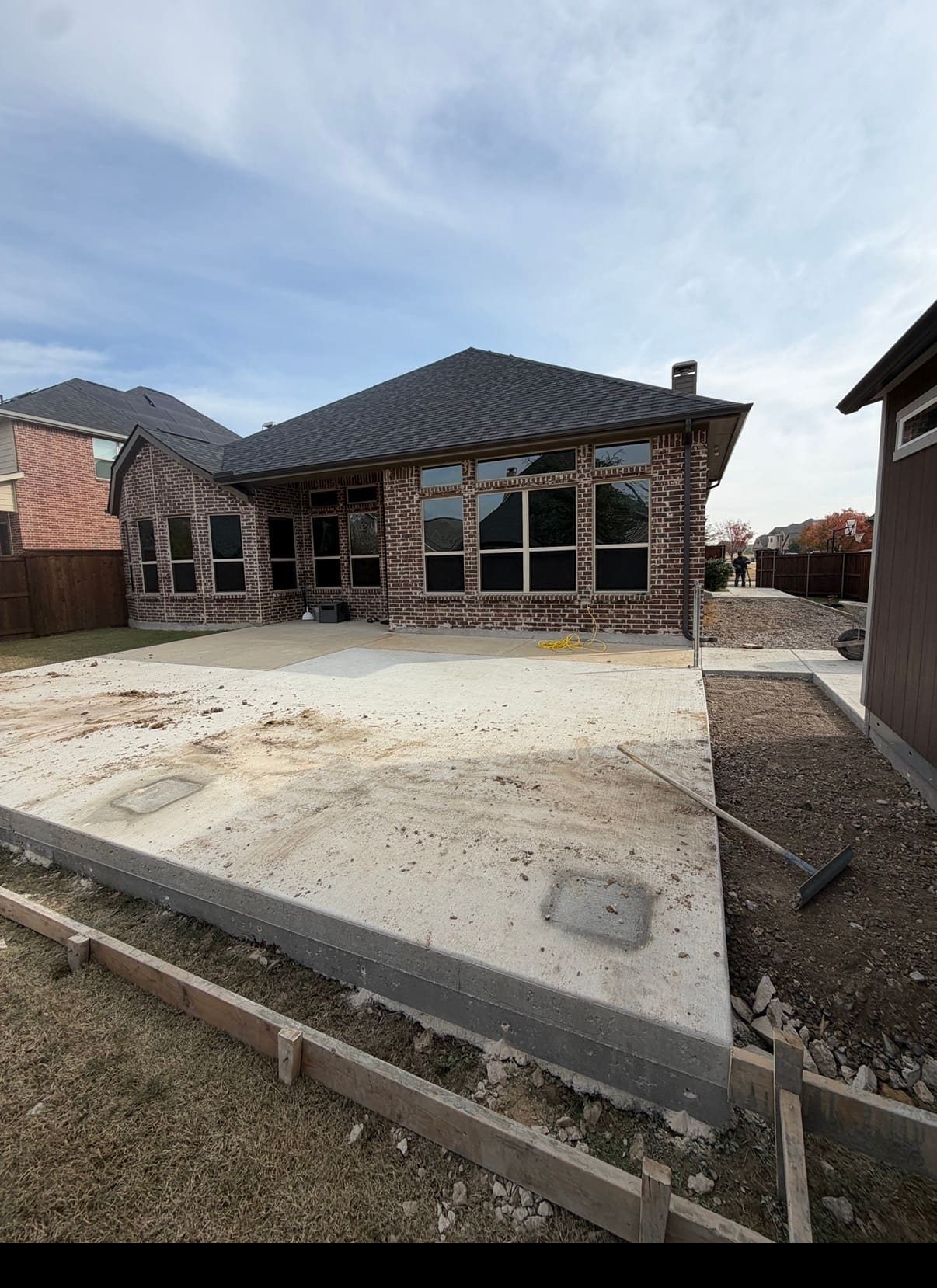 Freshly poured and finished concrete patio slab behind a brick home in Dallas-Fort Worth