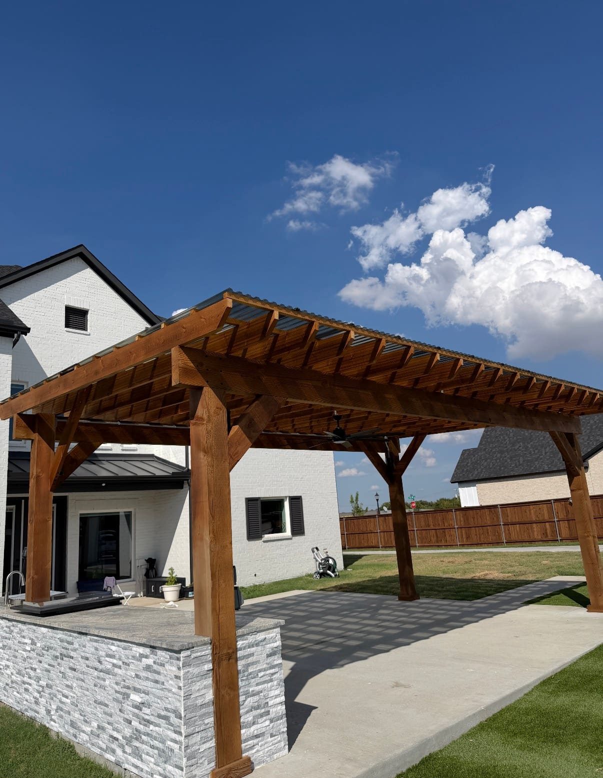Cedar patio cover with polycarbonate roof and stacked-stone outdoor kitchen island