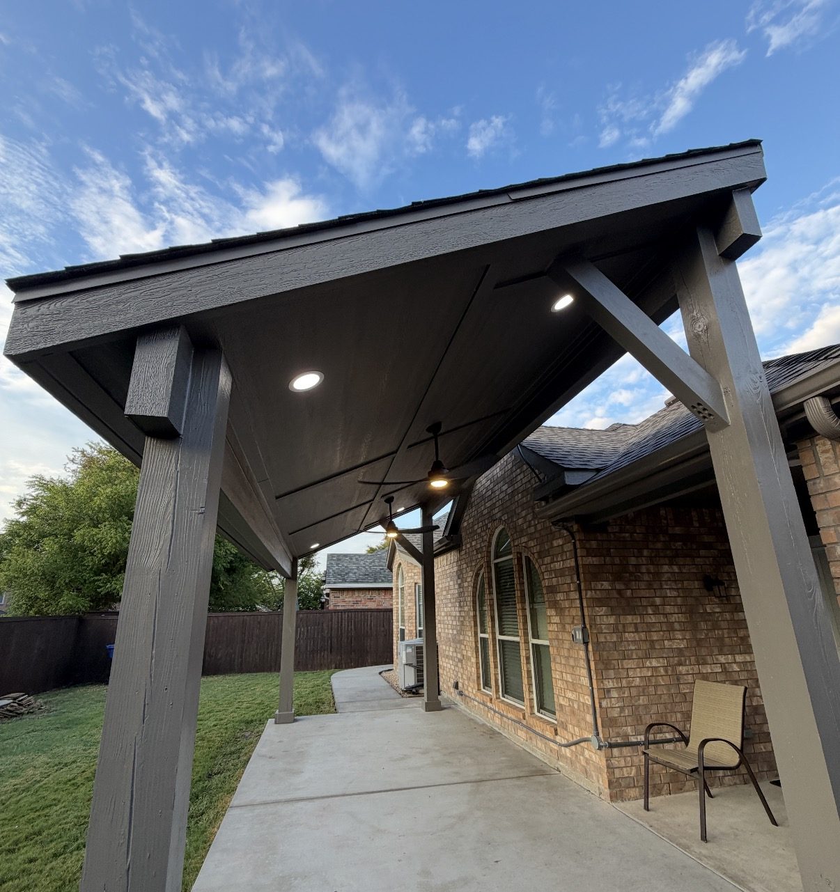 Underside of a charcoal patio cover roof with recessed lights and ceiling fans in Dallas-Fort Worth