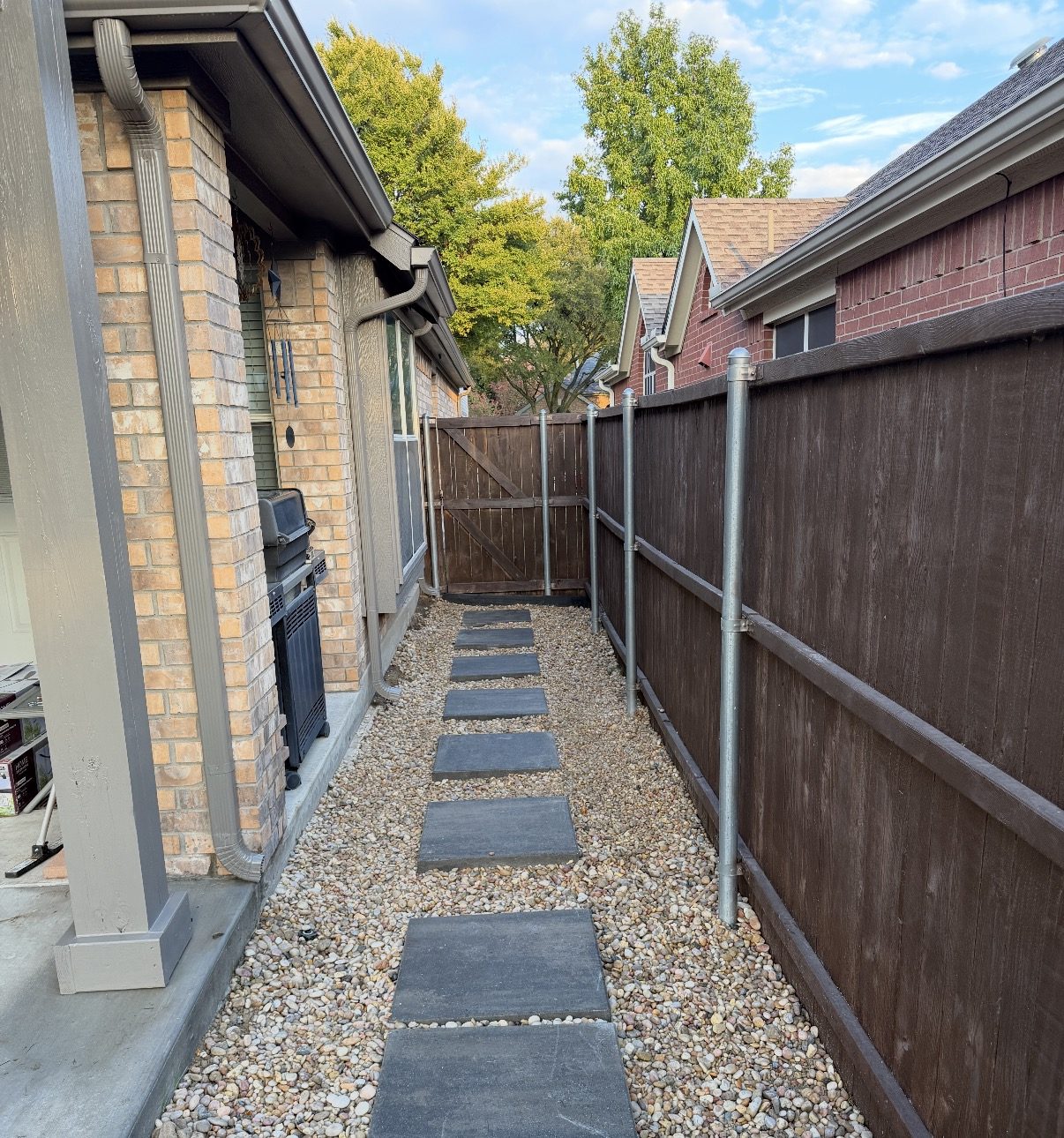 Large-format concrete pavers set in river rock along a fenced side yard in Dallas-Fort Worth